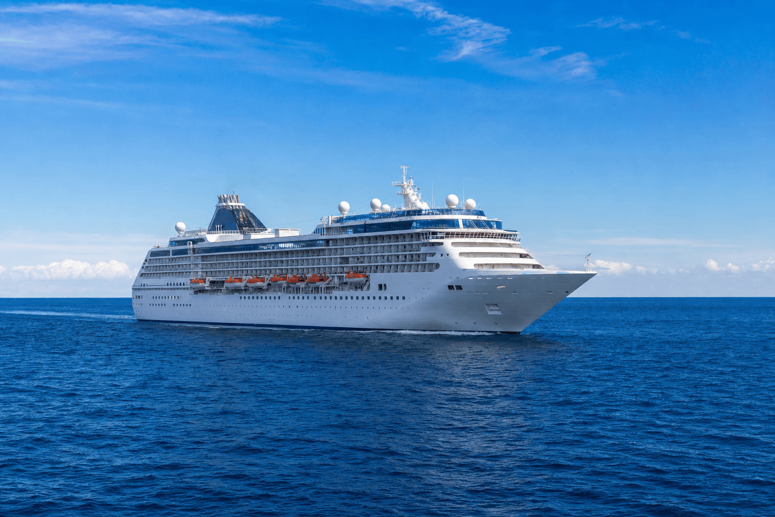 A large cruise ship sailing on open blue water under a bright sky