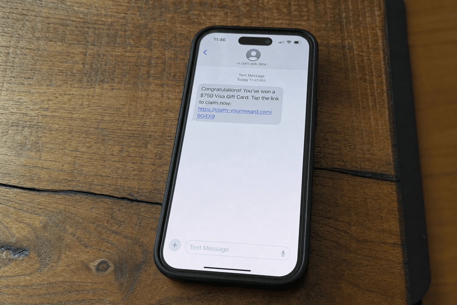 A smartphone lying flat on a table showing a text message claiming a gift card prize with a link